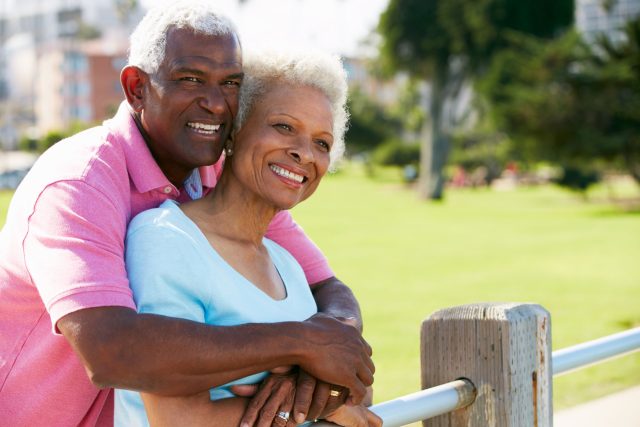 a man and a woman hugging each other by a fence.